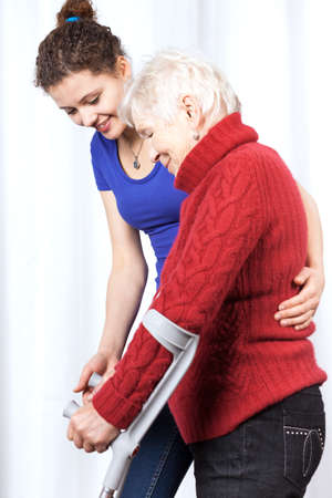 Elderly lady walking on crutches with young womanの写真素材