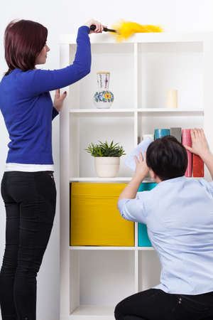 Daughter and her mother during dusting furniture