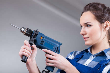 Beautiful independent woman using an electric drillの写真素材