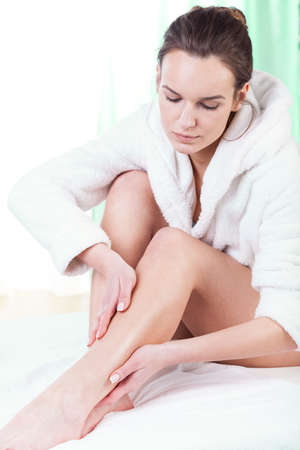 Woman rubbing lotion on her legs after depilation
