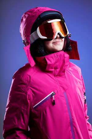 A woman in a pink winter jacket, goggles and a helmetの写真素材