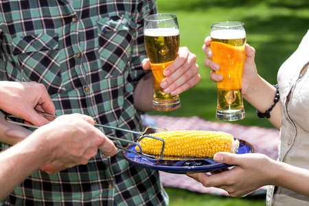 People dinking bear and eating fresh cornの写真素材