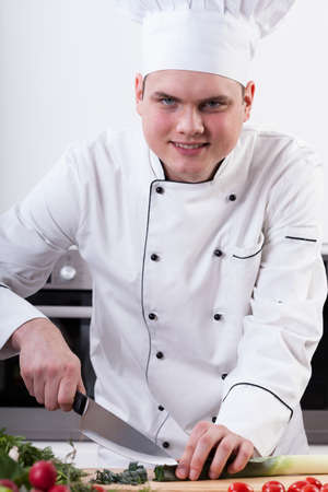 Cook cutting leek on wooden cutting boardの写真素材