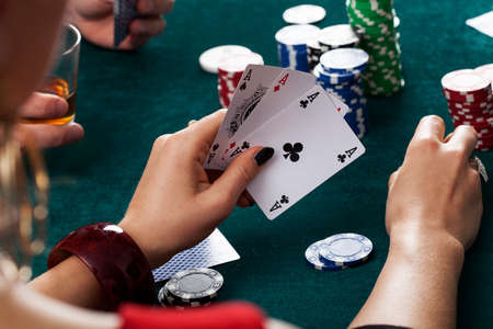 A closeup of a female gambler holding three aces