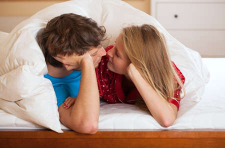 A couple under a quilt about to have some bed time kisses