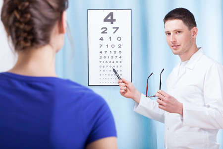 Young oculist doctor examining patient with tableの写真素材
