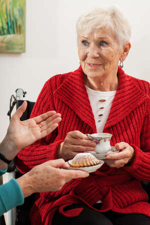 Elderly women talking, drinking tea and eating cupcakesの写真素材