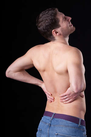 A man with no top on having painful lower back issues