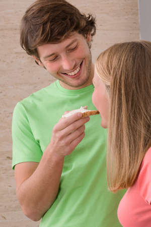 Man giving her girlfriend  a  tasty sandwichの写真素材