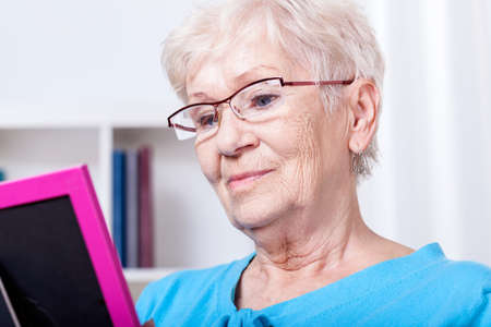 Elderly woman looking at photography in frameの写真素材