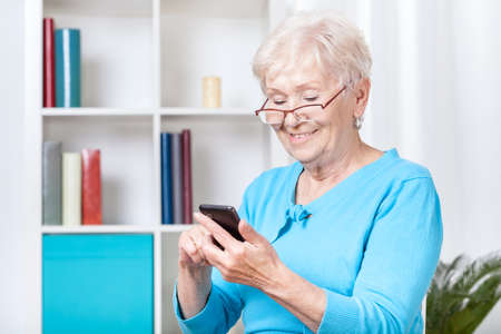 Smiley senior woman texting on mobile phone