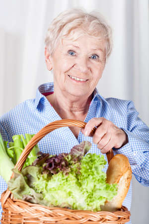Portrait of elderly woman holding basket with vegetablesの写真素材