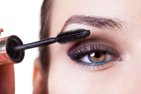 Young beautiful woman applying mascara on eyelashesの写真素材