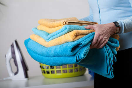A closeup of a pile of towels, an iron and a basket in the backgroundの写真素材