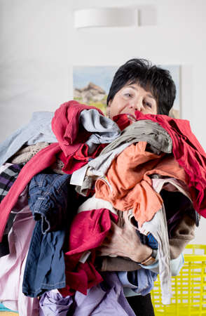 A woman holding a pile of dirty clothes to washの写真素材