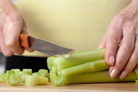 A closeup of a woman cutting a fresh green selery with a knifeの写真素材