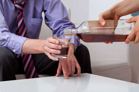 Bartender is pouring alcohol from bottle to glassの写真素材