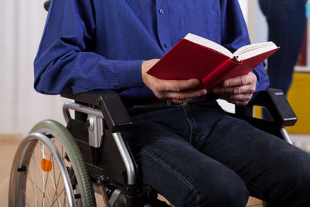 Horizontal view of a disabled man reading bookの写真素材