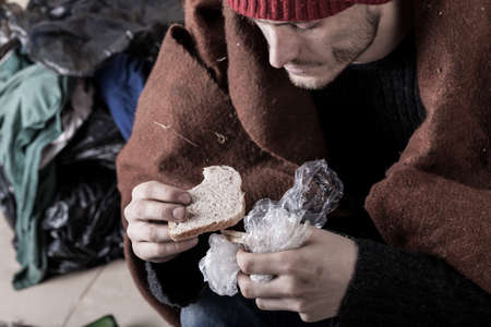 Poor man eating sandwich on the streetの写真素材