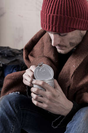 Homeless man eating preserve on the street