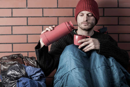 Homeless drinking hot tea on the streetの写真素材