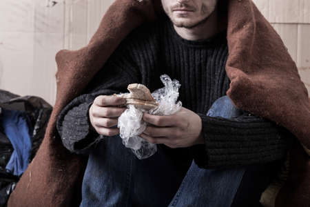 Homeless man eating sandwich on the streetの写真素材