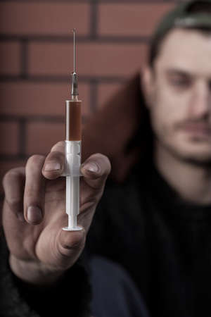Man addicted to drugs sitting on the streetの写真素材