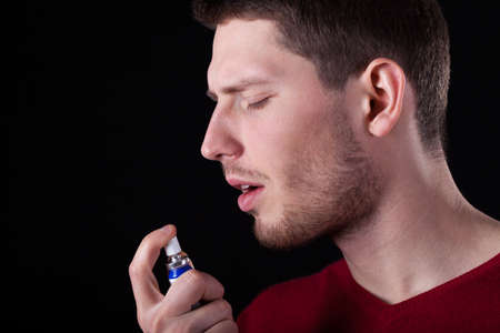 Man applying spray for sore throat, horizontalの写真素材