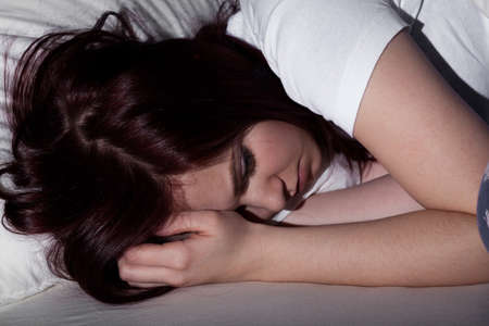 Young woman sleeping in bed at nightの写真素材