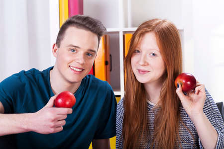 Happy male and female teenagers are holding applesの写真素材