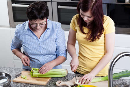 Women cutting celery and leek in kitchenの写真素材