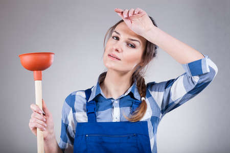 Tired, young woman with a plunger, horizontalの写真素材