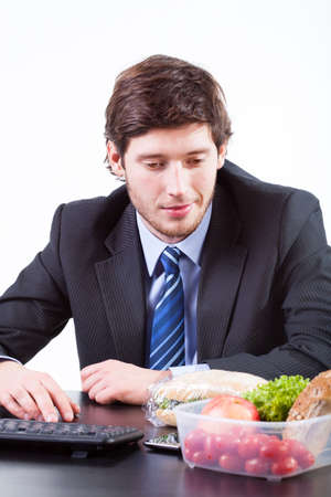 Young businessman looking for food in boxの写真素材
