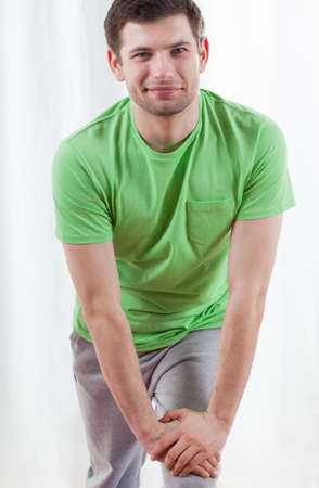 Portrait of young man stretching leg at gymの写真素材