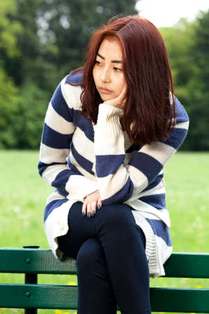 Sad mongolian woman sitting in the parkの写真素材