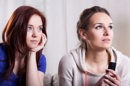 Close-up of two scared women watching televisionの写真素材