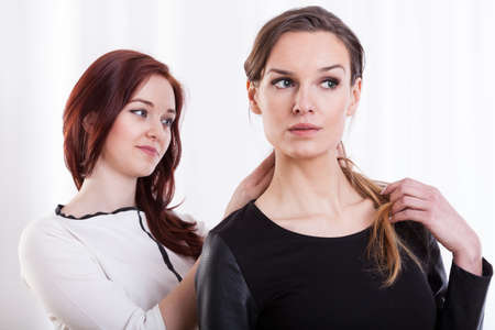Horizontal view of a woman combing hairs her friendの写真素材