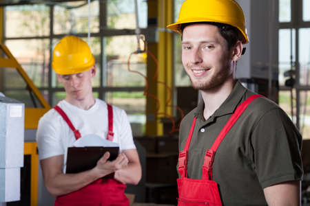 Horizontal view of two specialists working at factory