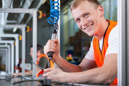 Close-up of a young smiling man working on the production lineの写真素材