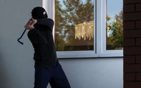 Burglar tries to smash a window in the buildingの写真素材