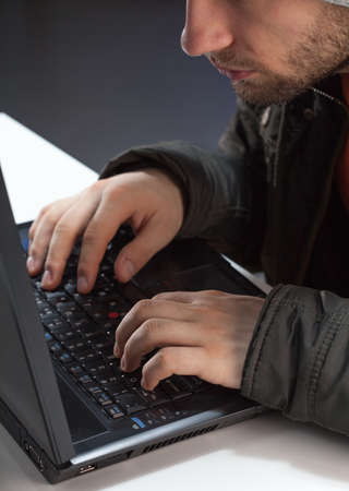 A closeup of a mysterious man hacking into a computer