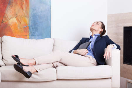 Young businesswoman resting on sofa after work の写真素材