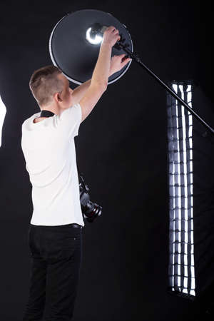 Back view of a photographer preparing lighting equipment の写真素材