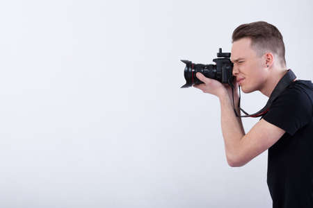 Side view of a young photographer on isolated white background