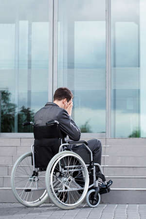 Stressful man on wheelchair before work in business centreの写真素材
