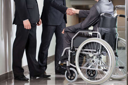 Handshake between disabled man and boss in officeの写真素材