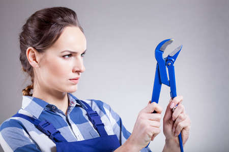 A woman striving to use a monkey wrenchの写真素材