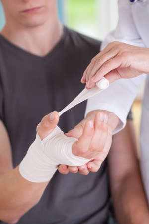 Female physician parcels man's wrist at her officeの写真素材