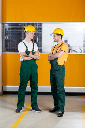 Vertical view of a factory workers standing with arms crossed and talkingの写真素材