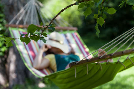 Woman sleeping on a hammock in gardenの写真素材